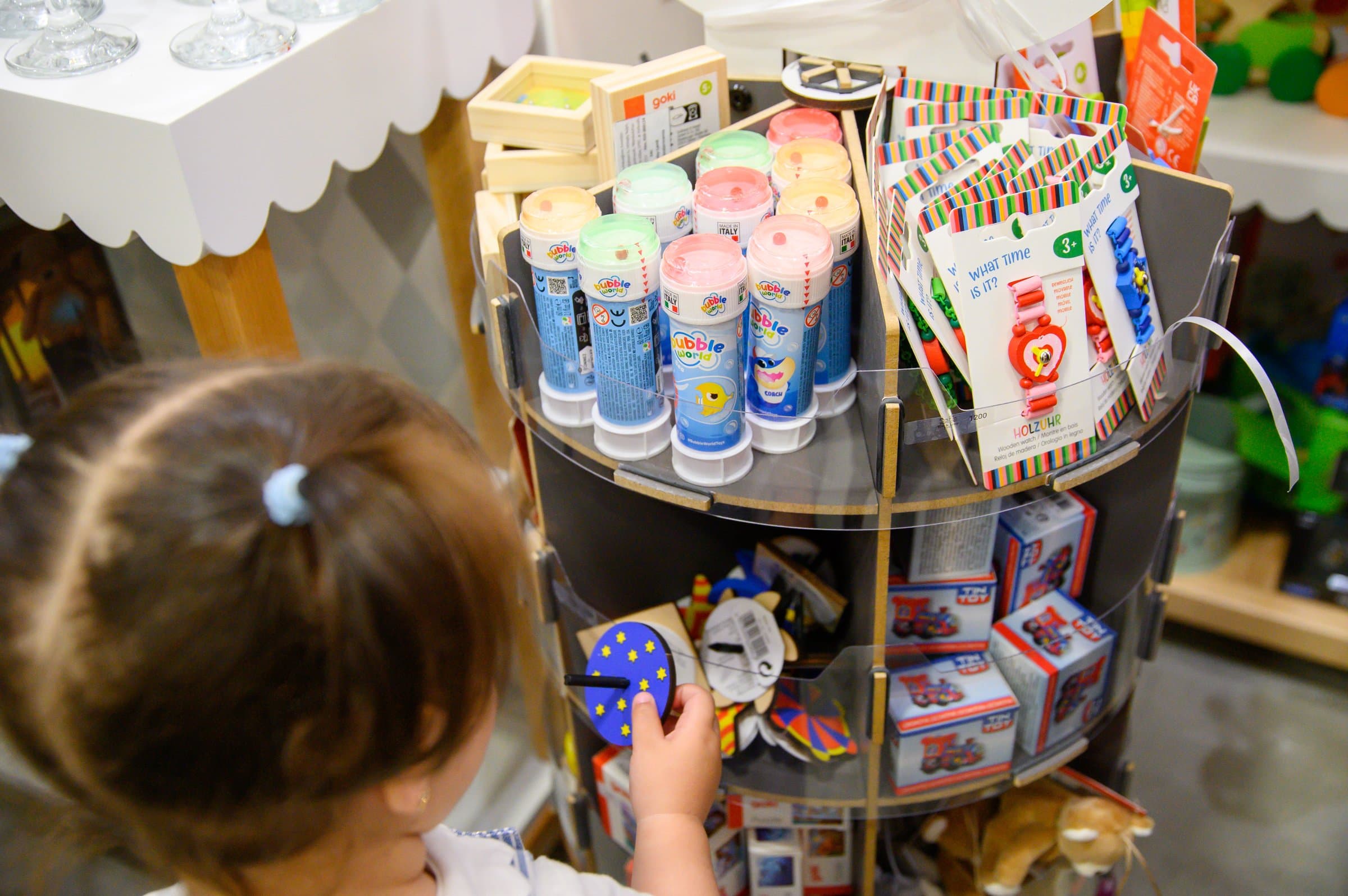 A toddler reaching for a toy on a display shelf at Max & Lizzy
