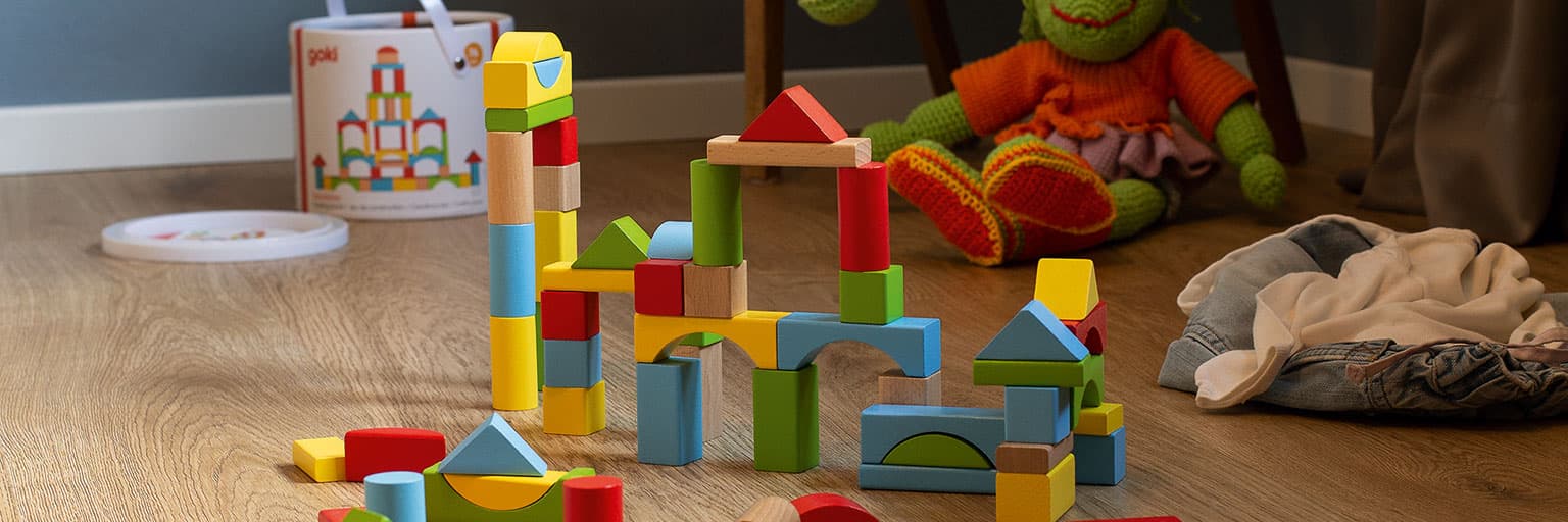 Colorful wooden building blocks stacked into an arch and towers on a wood floor